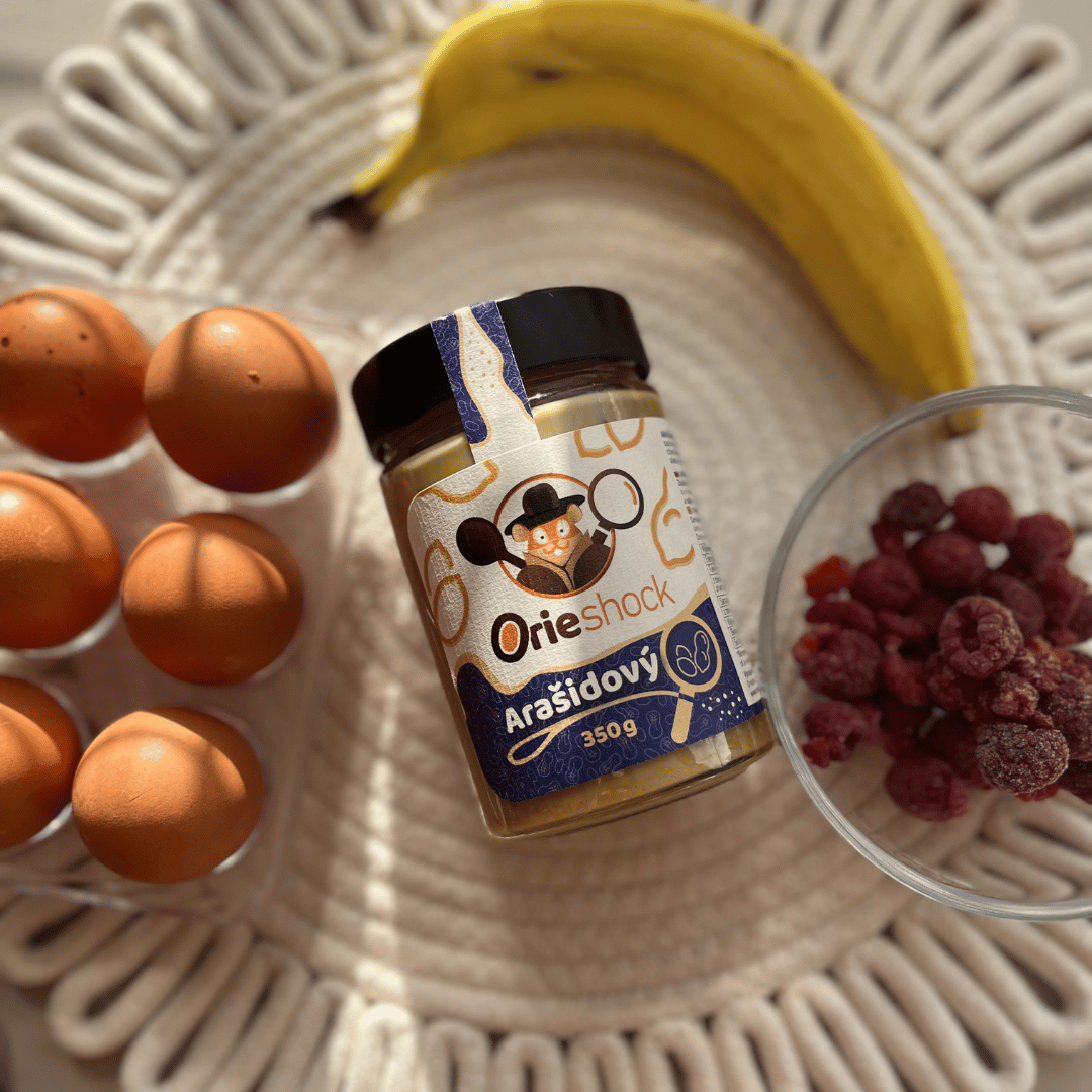Orieshock arašidový na ilustračnej fotografií k receptu na arašidové waffle len z 2 ingrediencií. Na stole je položený Orieshock 350g, vajíčka a banán.